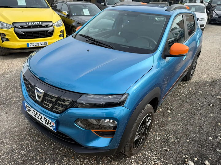 Dacia Spring bleue mise en scène dans un studio gris perle - photo d'origine