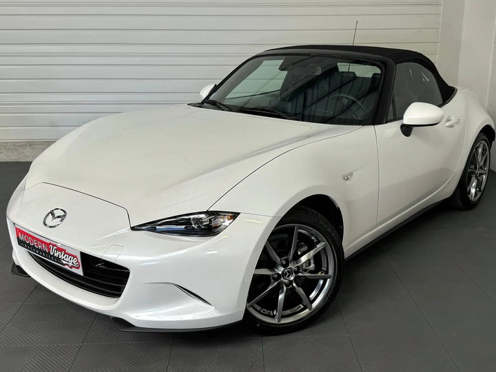 Mazda MX-5 blanc nacré mise en scène dans une clairière boisée - photo d'origine